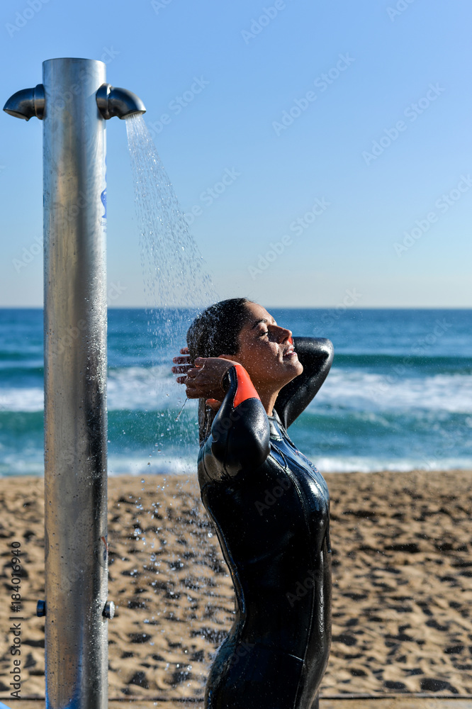 Female standing under shower on beach Female standing under shower on beach