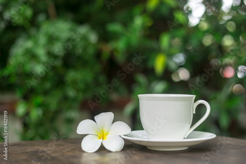 Fototapeta Naklejka Na Ścianę i Meble -  Hot cup of coffee with white flower decor on table