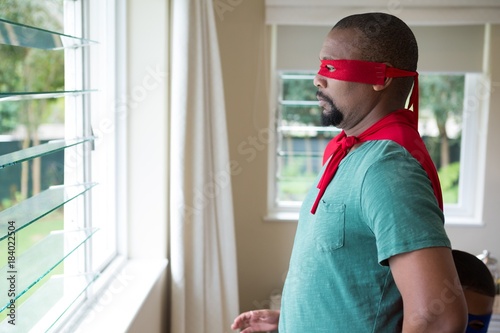 Man in superhero costume looking through window