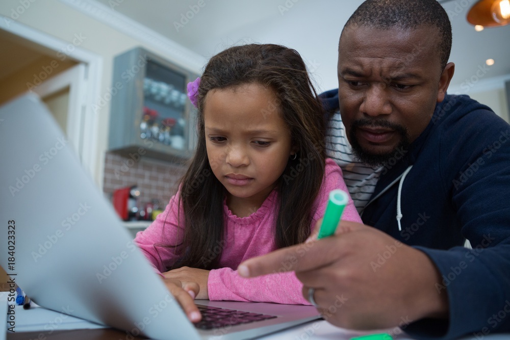 Father and daughter using laptop in kitchen Father and daughter using laptop in kitchen