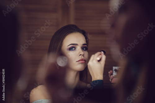 Make-up artist doing makeup to girl in studio.