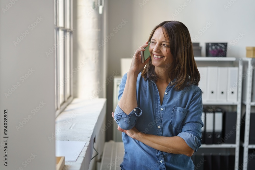 lächelnde frau im büro telefoniert mit ihrem smartphone