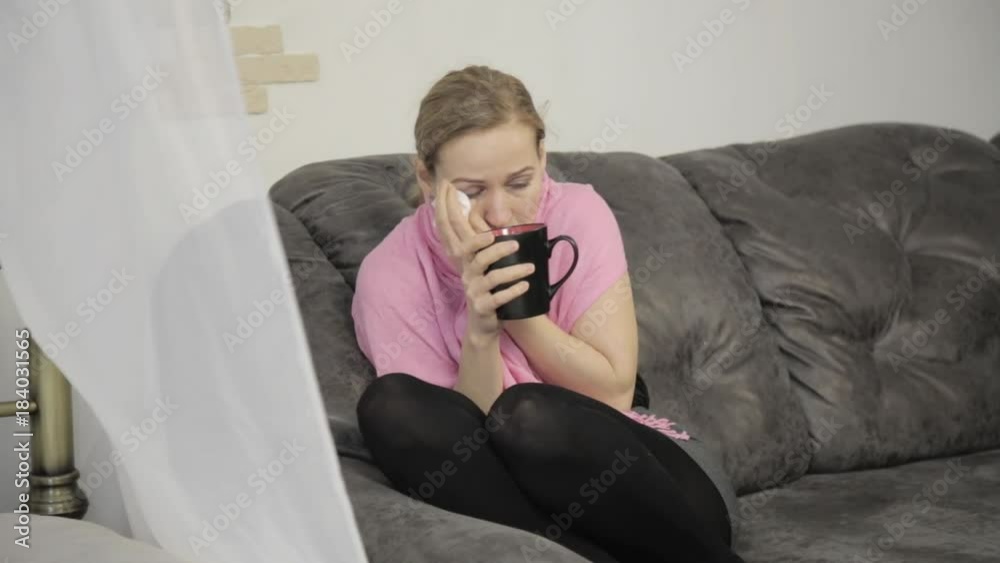 sick woman wipes his nose using a napkin and sheltered by a warm blanke
