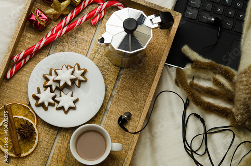 Cozy Christmas at home. Christmas breakfast in bed, a cup of coffee and cookies, next to a laptop 
