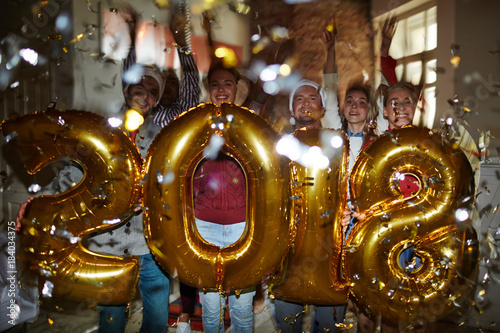 Excited guys and girls holding golden inflatable numbers and making 2018