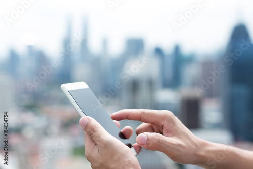 man's hand with mobile phone in modern city