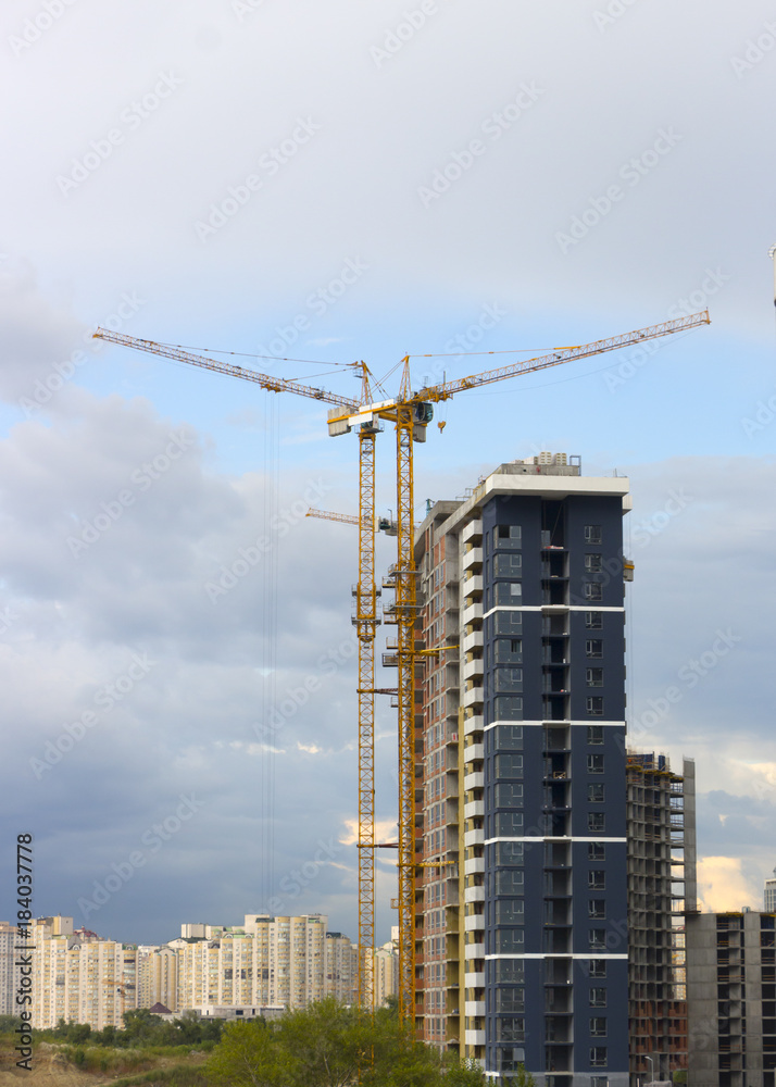 tower crane against the blue sky, the process of building a multi-storey building