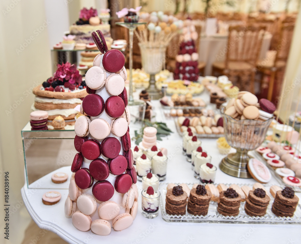 Wedding decoration with pastel colored cupcakes, meringues, muffins and macaroons. Elegant and luxurious event arrangement with colorful macaroons. Wedding dessert with macaroons