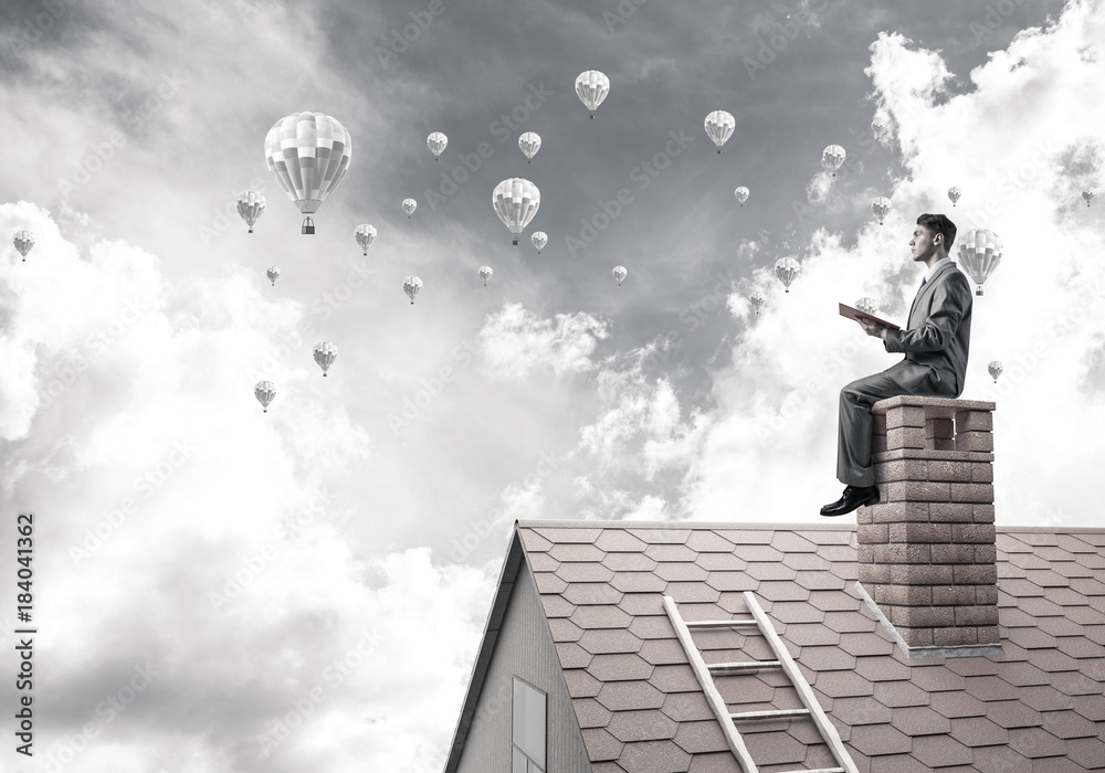 Man on roof reading book and aerostats flying in air Man on roof reading book and aerostats flying in air