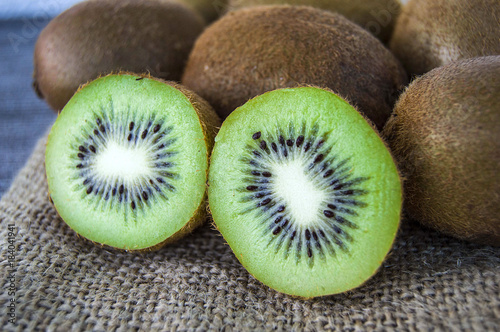 kiwi fruit, two pieces of kiwi with knife, kiwi standing on wooden floor
