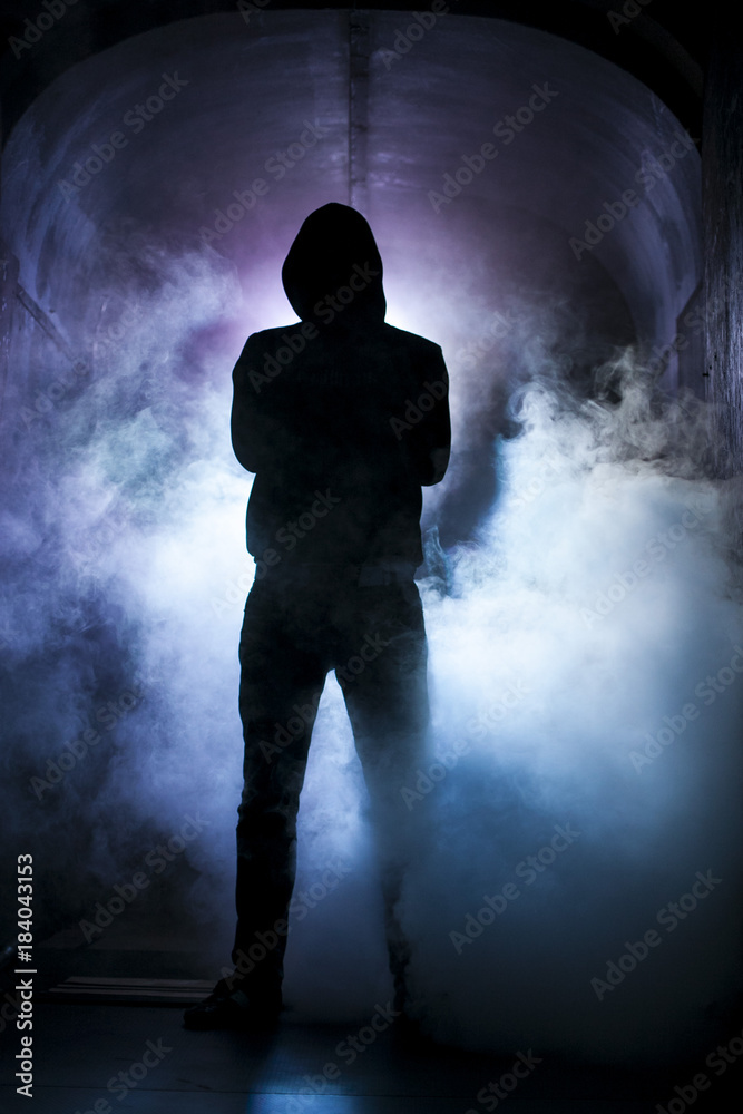 Silhouette of a man with a hood in blue light