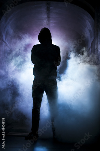 Silhouette of a man with a hood in blue light