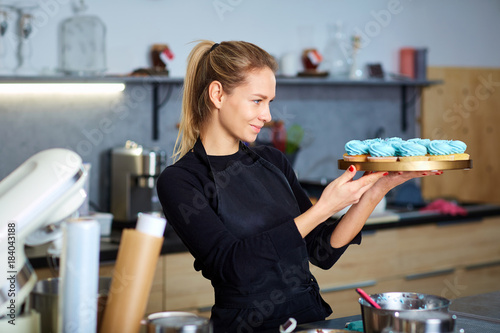 фотографія Confectioner pastry woman holding a tray of cupcakes in the kitchen