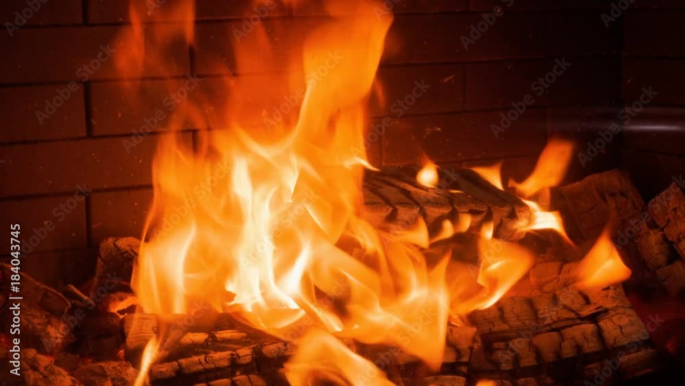 Home interior. Close-up shot of warm cozy burning fire in a brick fireplace. 4K Home interior. Close-up shot of warm cozy burning fire in a brick fireplace. 4K