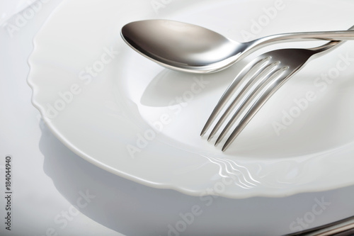 Empty plate with spoon and fork on a white background