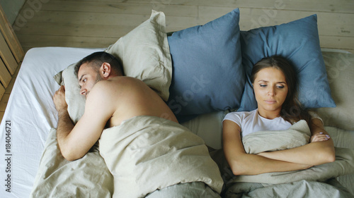 Top view of upset lying sleepless couple in bed offended because of quarrel