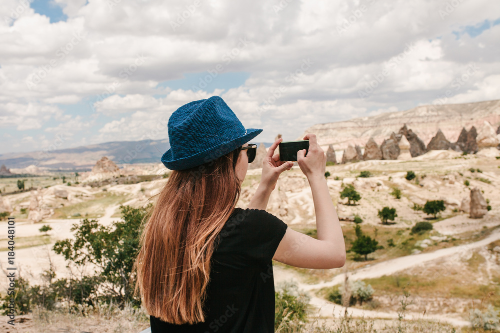 Fototapeta premium A tourist makes a photo on the phone in memory of a beautiful view of the hills in Cappadocia in Turkey. Travel, tourism, vacation.