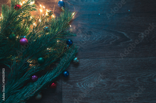 Christmas tree branches with Christmas decorations on a wooden background.
