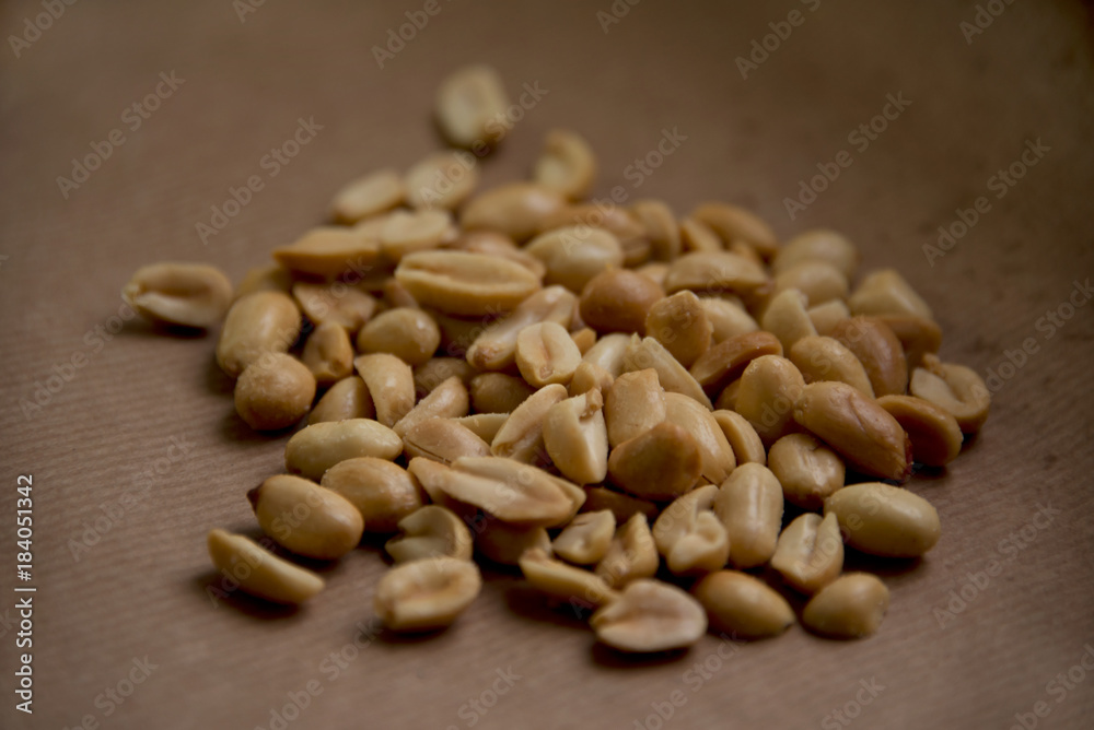 Roasted, salted peanuts on brown paper Roasted, salted peanuts on brown paper