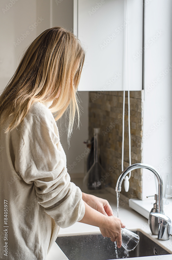 Woman hands washing dish or pouring glass with running fresh drink water at kitchen faucet Woman hands washing dish or pouring glass with running fresh drink water at kitchen faucet