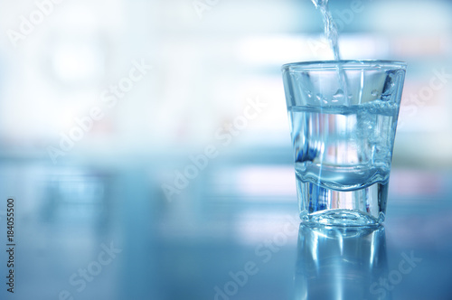 single glass shot with movement water for drinking in blue background