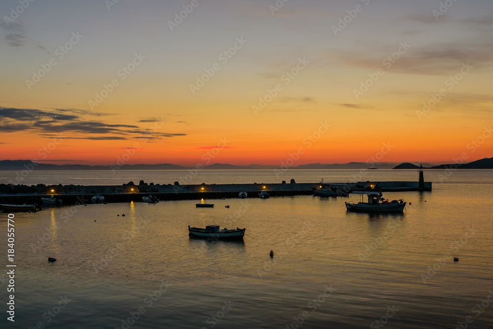 A beautiful sunrise at the sea. Pier with fishing boats in Kokkari village, Samos island, Greece