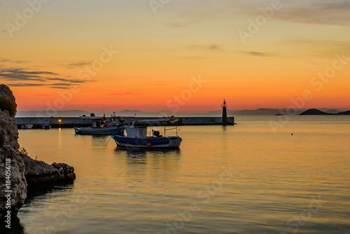 A beautiful sunrise at the sea. Pier with fishing boats in Kokkari village, Samos island, Greece