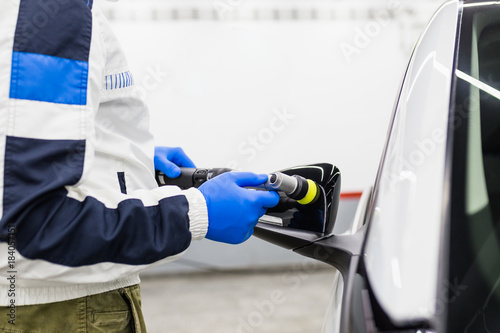 Car detailing - Worker with orbital polisher in auto repair shop. 