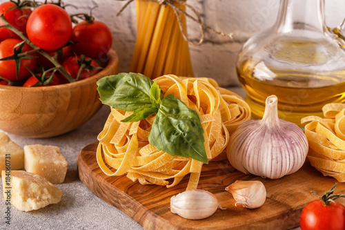 Products for cooking - pasta, tomatoes, garlic, olive oil, basil.