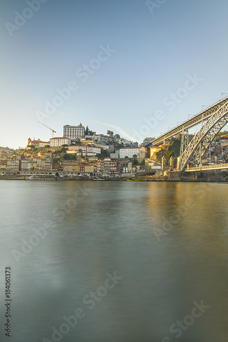 Portrait wide-angle sunset view of Porto City, Downtown/Harbour with Douro River in front and Ponte Luís I Bridge on the right side; Cathedral and tower crane in background; Portugal/Europe
