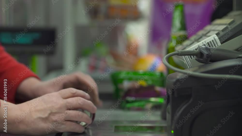 Close up check out counter. Senior female hands working on cash register in the supermarket