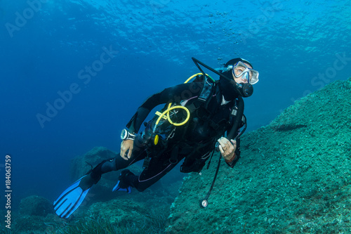 woman scuba diving over rocks in the Mediterranean Sea