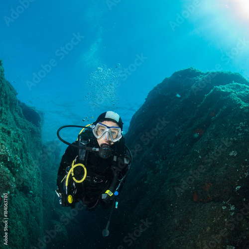 woman scuba diving over rocks in the Mediterranean Sea photo