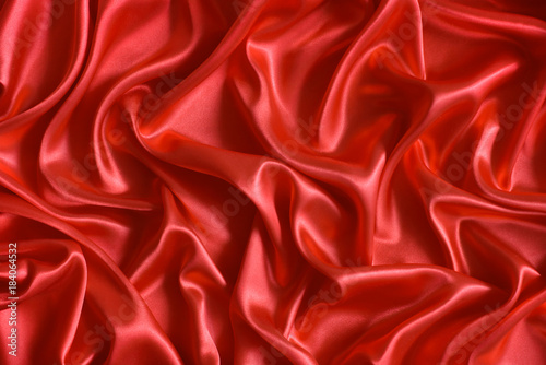 Close up of ripples in red silk fabric. Satin textile background.