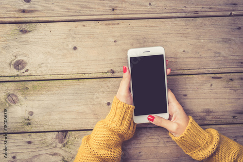 Woman using a white smartphone in warm sweater  photo