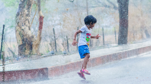 Photos Cute liitle girl dancing and welcoming the first monsoon showers by playing in h
