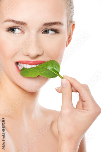 Beautiful caucasian woman eating fresh green leaf.