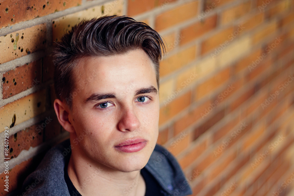 Close up of handsome young man against brick wall Close up of handsome young man against brick wall