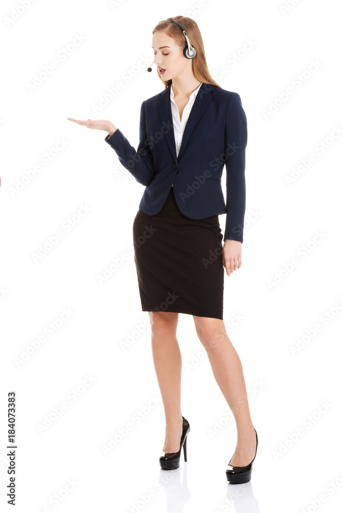 Beautiful causual business woman at call center is pointing on copy space. Beautiful causual business woman at call center is pointing on copy space.