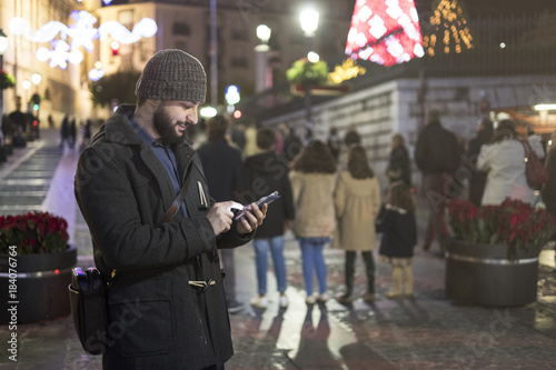 Man in christmas night image sending sms by smarphone app