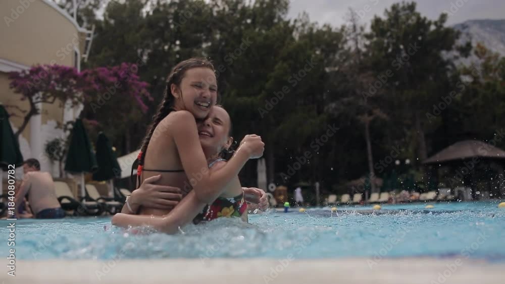 little happy girls doing splashes and laughing in pool little happy girls doing splashes and laughing in pool