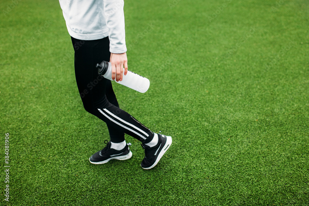 Obraz premium Running girl holding a bottle of water. The girl made a break, after a good workout.