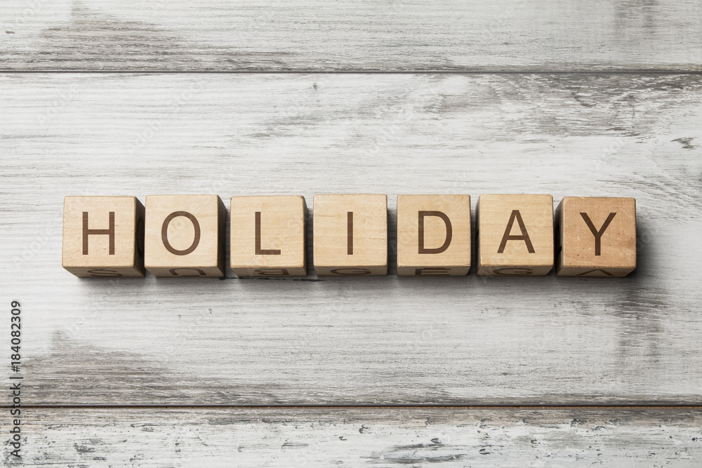 HOLIDAY word written on wooden cubes on wooden background