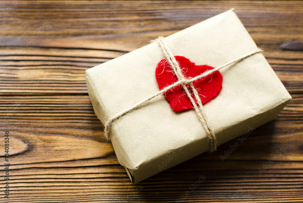 gift box wrapped in kraft paper and red wooden heart on wooden table gift box wrapped in kraft paper and red wooden heart on wooden table