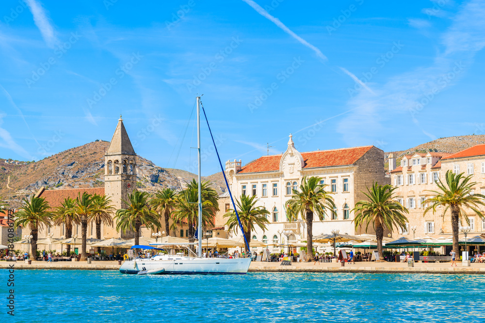 Fototapeta premium Sailing boat anchoring in Trogir town with historic buildings in background, Dalmatia, Croatia