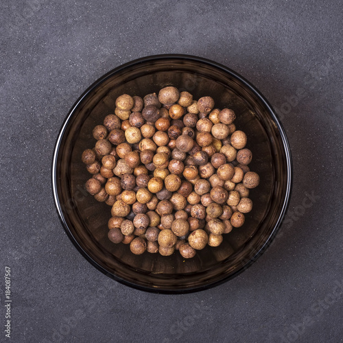 Pimento spice in a bowl on a grey concrete background