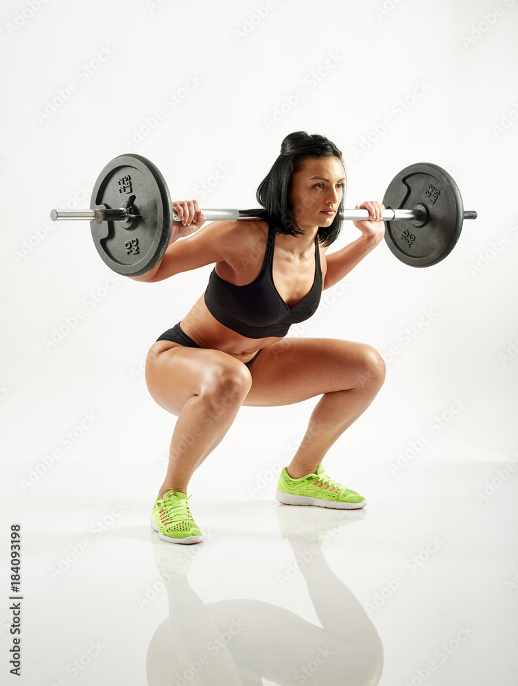 Obraz premium Young woman doing barbell squats
