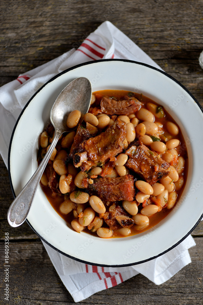 White beans stewed with smoked ribs, onions, carrots, garlic, red paprika, tomatoes and parsley. White beans stewed with smoked ribs, onions, carrots, garlic, red paprika, tomatoes and parsley.