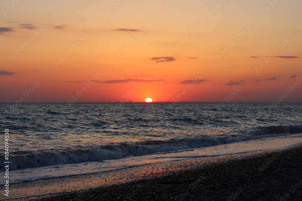 Fiery red sunset over the sea, the silhouette of the city