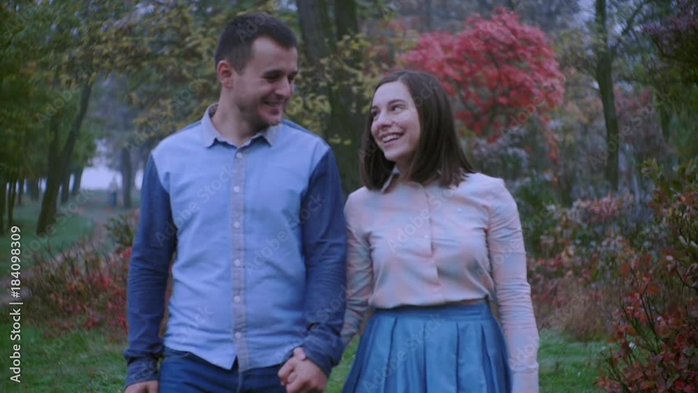 Young couple in love holding hands and walking through a park on a autumn day Young couple in love holding hands and walking through a park on a autumn day